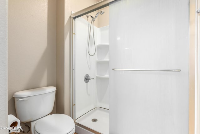 bathroom with toilet and a shower with door