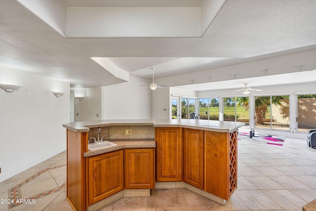 kitchen featuring a textured ceiling, sink, light tile patterned floors, and a kitchen island