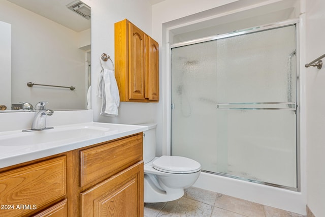 bathroom featuring a shower with door, vanity, toilet, and tile patterned floors