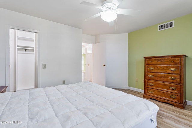 bedroom with a spacious closet, light hardwood / wood-style flooring, a closet, and ceiling fan