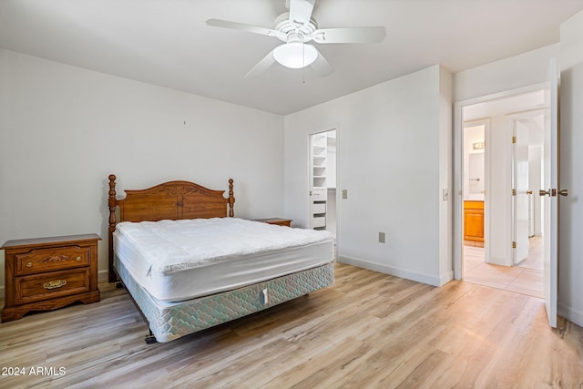 bedroom with a closet, light hardwood / wood-style floors, a walk in closet, and ceiling fan