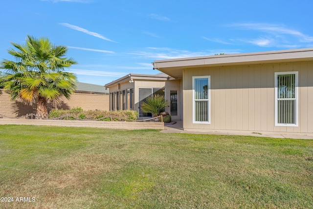 back of house with a yard and a sunroom