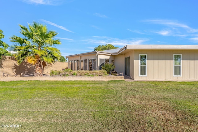 rear view of property featuring a sunroom and a lawn