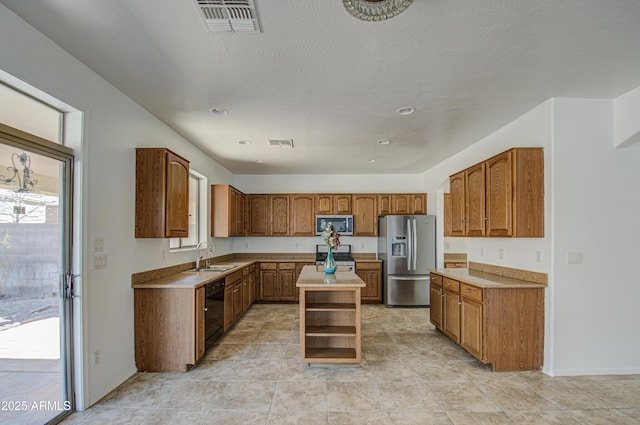 kitchen featuring visible vents, a kitchen island, appliances with stainless steel finishes, and light countertops