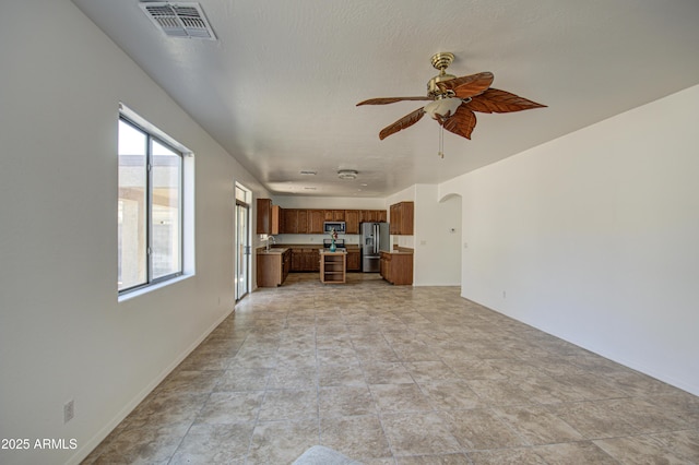 interior space with arched walkways, a sink, visible vents, and a ceiling fan