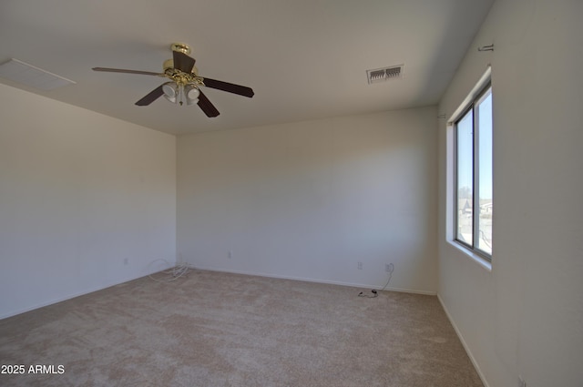 empty room with baseboards, visible vents, ceiling fan, and light colored carpet