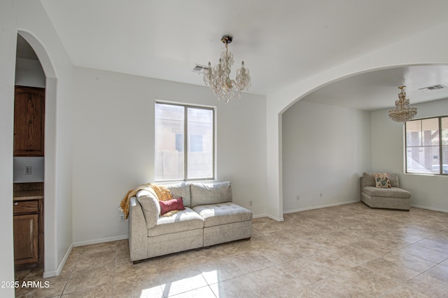 living room featuring an inviting chandelier, baseboards, visible vents, and arched walkways