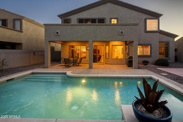 back of house with stucco siding, a patio, a fenced in pool, and fence