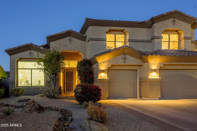 mediterranean / spanish-style home with concrete driveway, an attached garage, and stucco siding