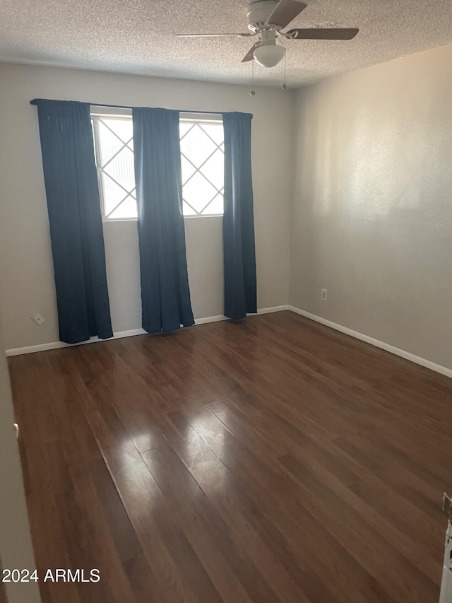 unfurnished room with ceiling fan, a textured ceiling, and dark hardwood / wood-style floors