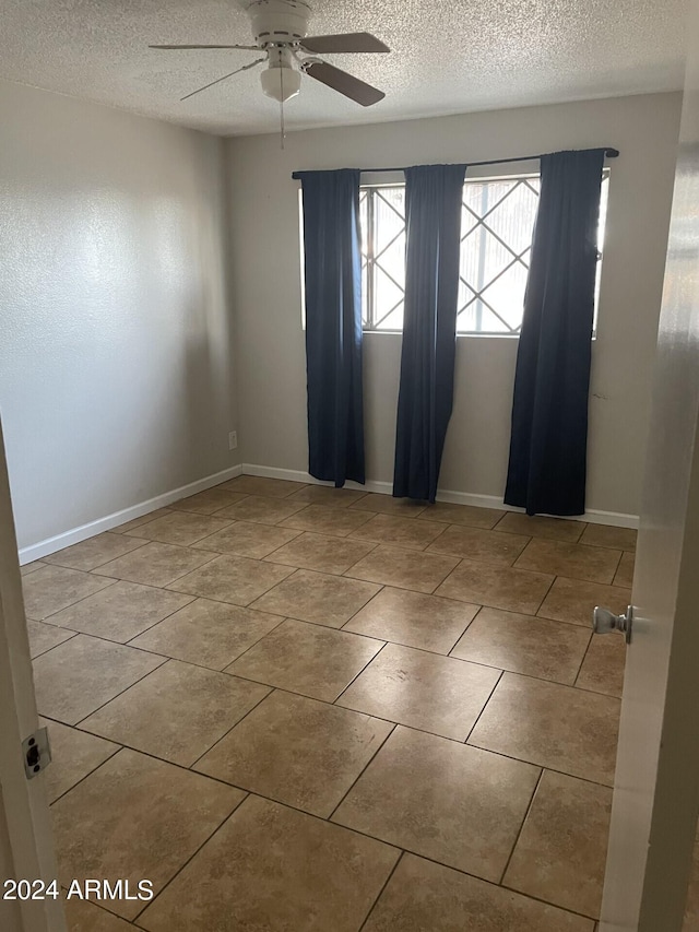 spare room featuring ceiling fan, a textured ceiling, and light tile patterned floors