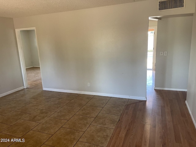 empty room featuring a textured ceiling and dark hardwood / wood-style flooring