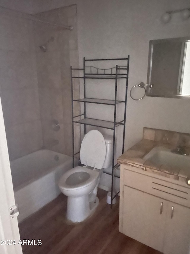 full bathroom with toilet, tiled shower / bath, vanity, and wood-type flooring