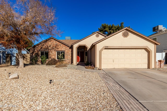 single story home featuring central AC unit and a garage