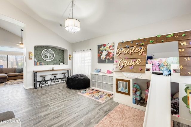 rec room with ceiling fan, hardwood / wood-style floors, and vaulted ceiling