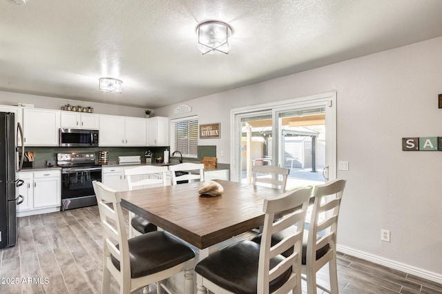 dining room featuring hardwood / wood-style floors, sink, and a textured ceiling