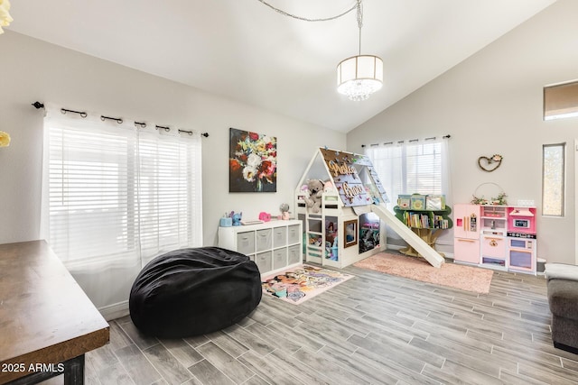 rec room with a notable chandelier, light wood-type flooring, and high vaulted ceiling