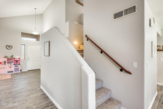 stairs with a towering ceiling and wood-type flooring