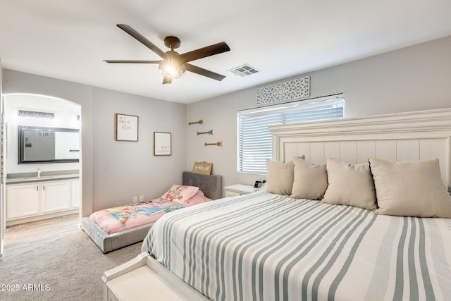 carpeted bedroom featuring ceiling fan, sink, and ensuite bath