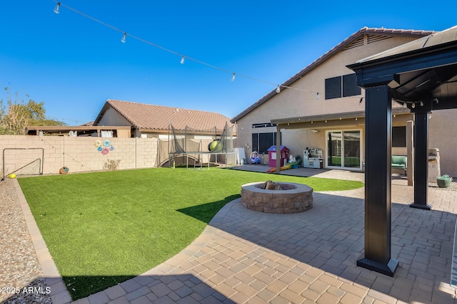 view of yard featuring a patio, a trampoline, and an outdoor fire pit