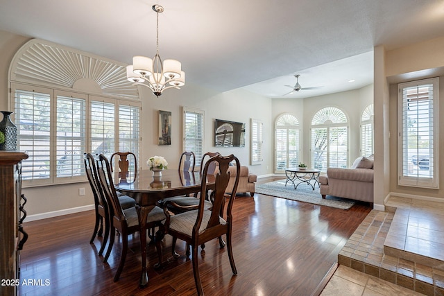 dining area with baseboards, dark wood-style flooring, and ceiling fan with notable chandelier