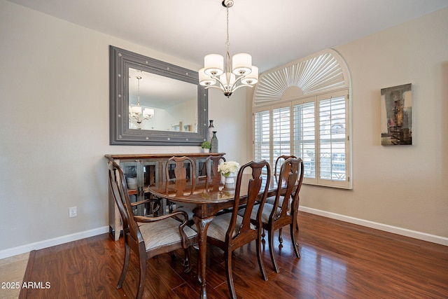 dining space with baseboards, wood finished floors, and an inviting chandelier