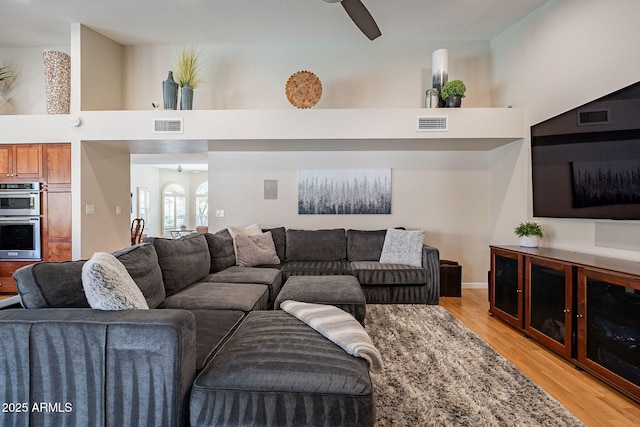 living area with visible vents, light wood-style flooring, and a high ceiling