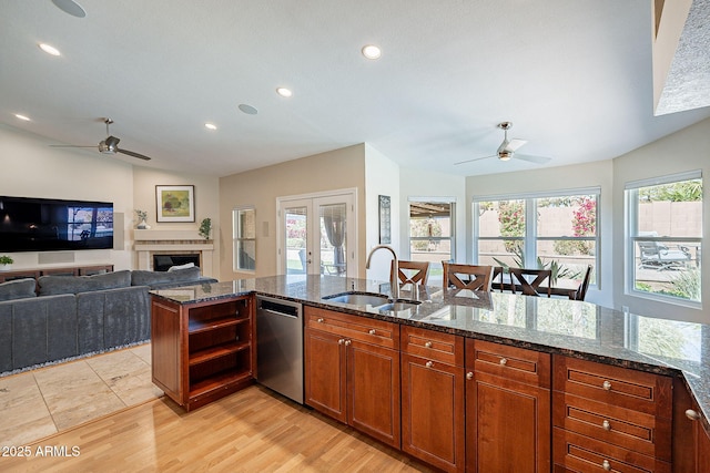 kitchen featuring a sink, open floor plan, french doors, stainless steel dishwasher, and dark stone countertops