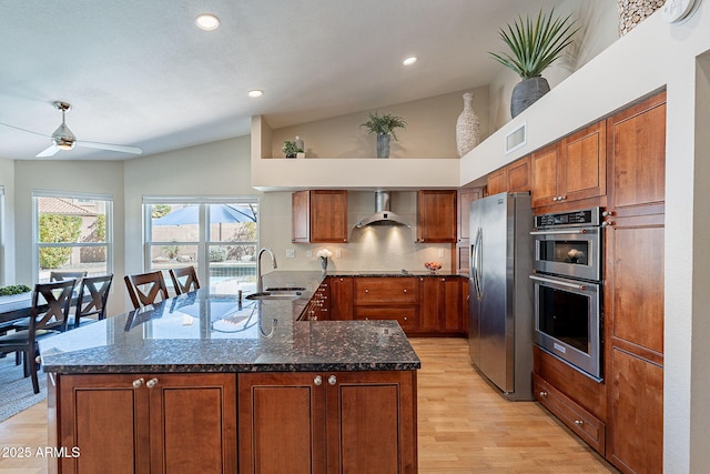 kitchen featuring a sink, visible vents, appliances with stainless steel finishes, wall chimney exhaust hood, and brown cabinetry