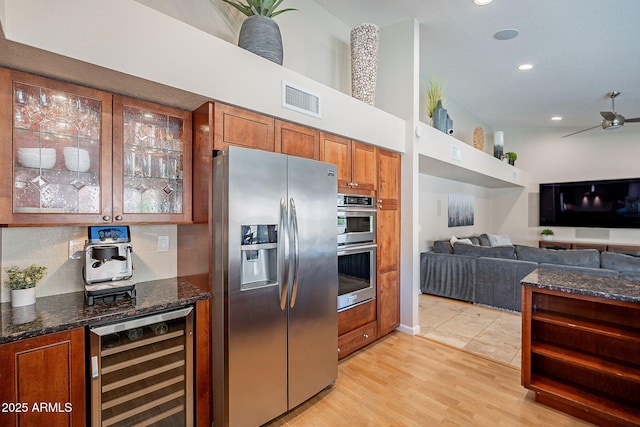 kitchen featuring wine cooler, stainless steel appliances, visible vents, glass insert cabinets, and dark stone countertops