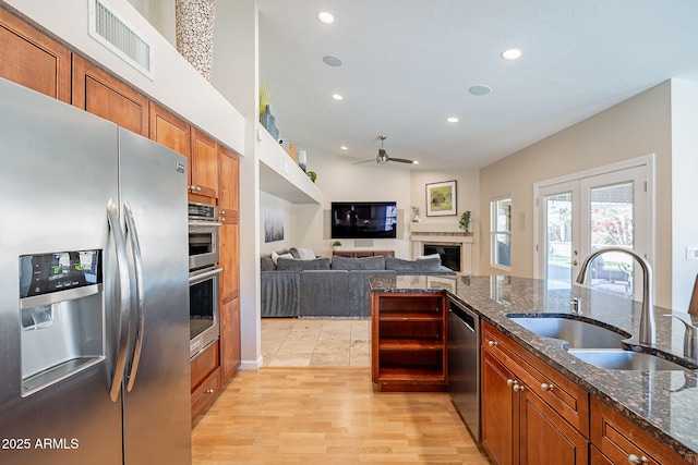 kitchen with appliances with stainless steel finishes, visible vents, a sink, and dark stone countertops