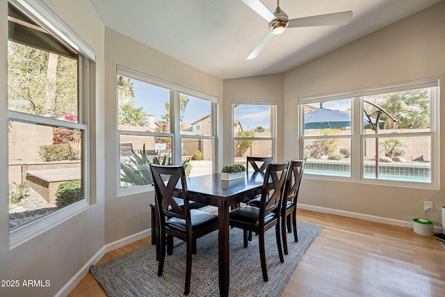 dining space featuring light wood-type flooring, lofted ceiling, and baseboards