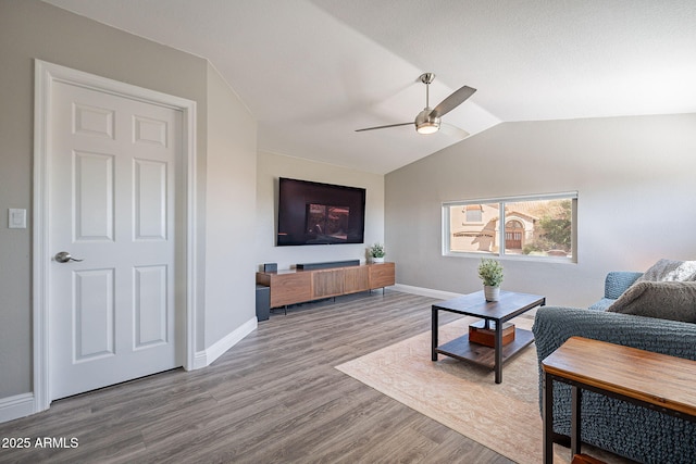 living room featuring light wood-type flooring, lofted ceiling, ceiling fan, and baseboards