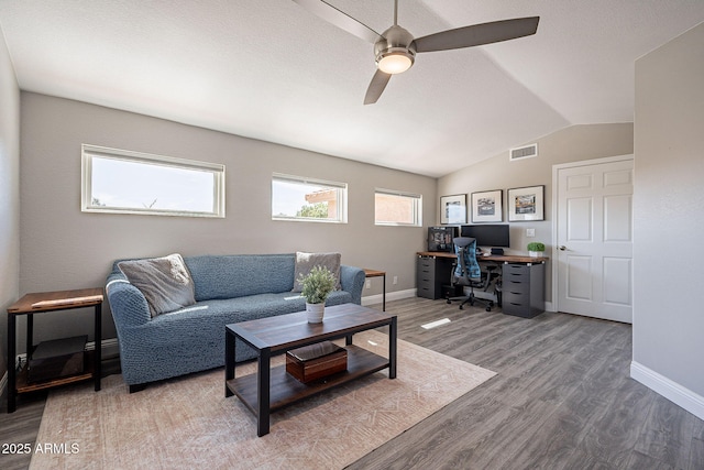 living room featuring lofted ceiling, baseboards, visible vents, and wood finished floors