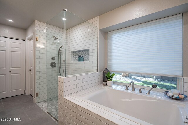 bathroom featuring tile patterned flooring, a closet, a garden tub, and a walk in shower