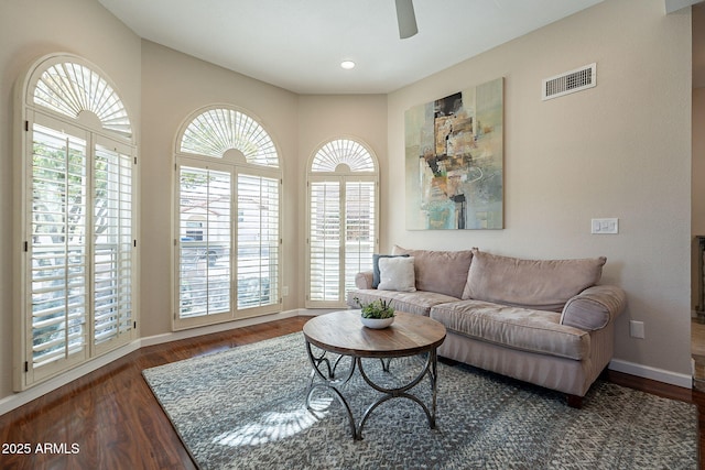 living room featuring dark wood-style flooring, visible vents, and baseboards