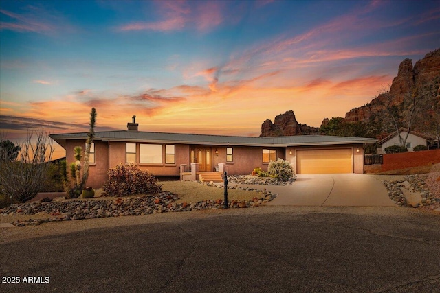 single story home with driveway, a chimney, an attached garage, and stucco siding