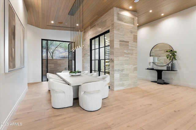 dining space with wooden ceiling, light hardwood / wood-style floors, and a high ceiling