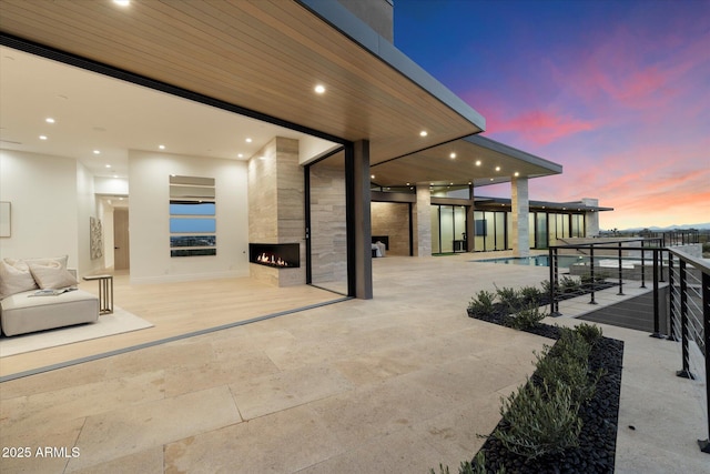 patio terrace at dusk featuring a large fireplace