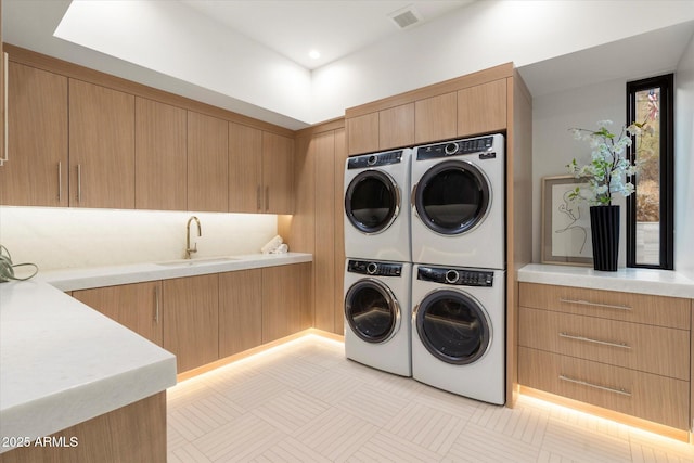 laundry room with cabinets, stacked washing maching and dryer, washer and clothes dryer, and sink