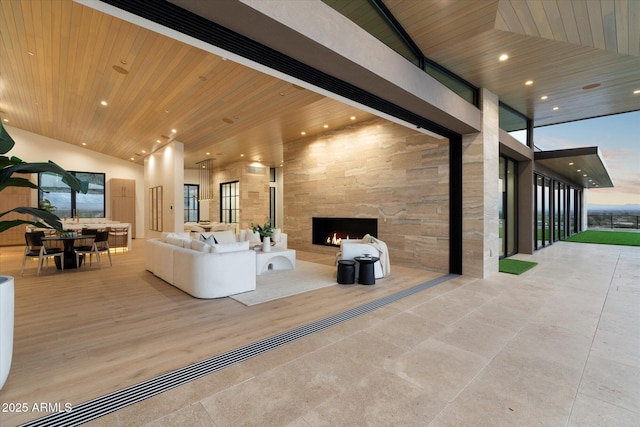 living room with an outdoor fireplace and wooden ceiling