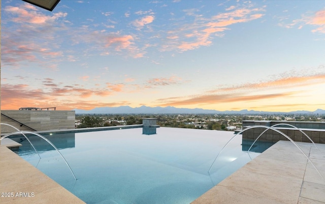 pool at dusk with a mountain view and pool water feature