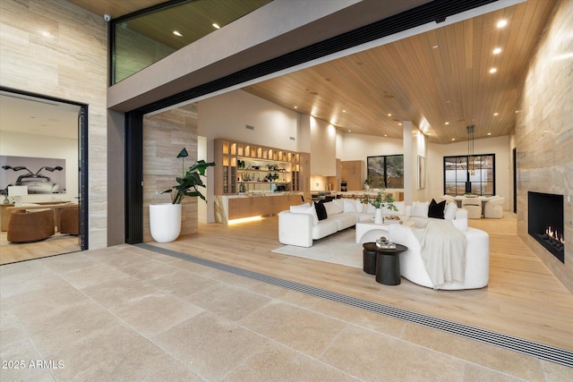 living room featuring a fireplace, wooden ceiling, and a high ceiling