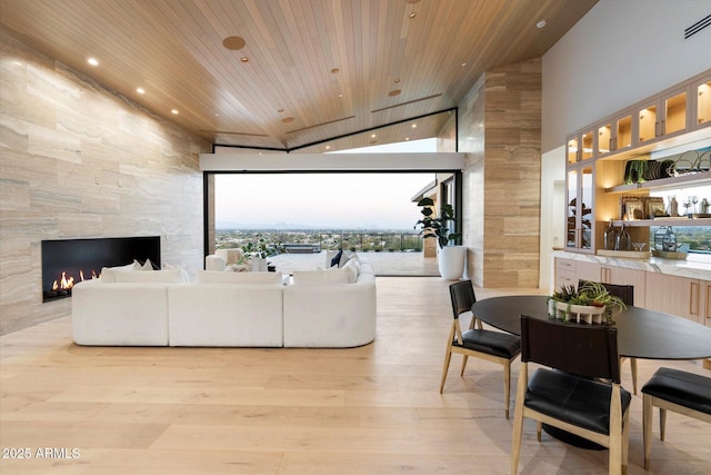 living room featuring a fireplace, wood ceiling, a wall of windows, and light wood-type flooring