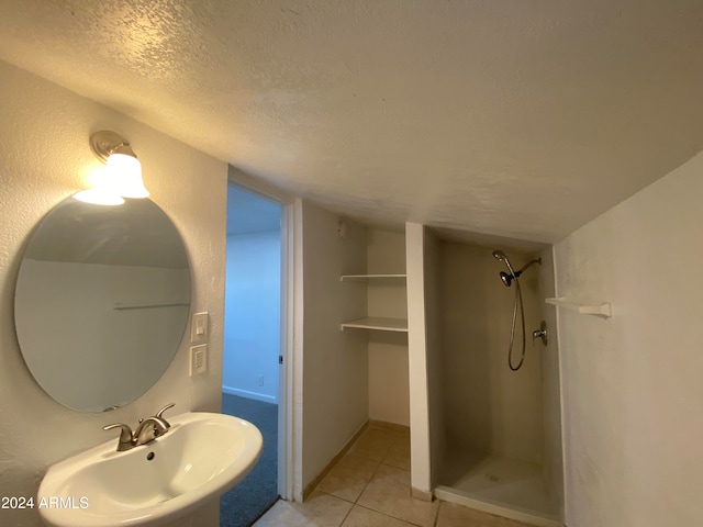 bathroom with walk in shower, sink, tile patterned floors, and a textured ceiling