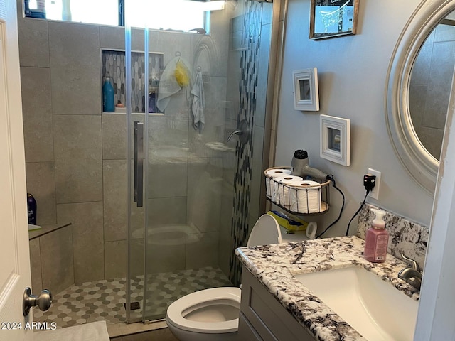 bathroom featuring a shower with door, vanity, and toilet