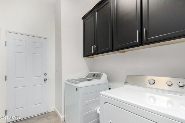 clothes washing area featuring washer and clothes dryer and cabinets