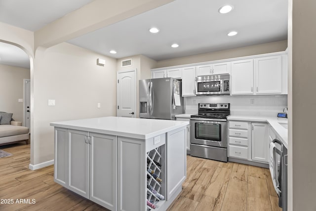 6819 N 10th Pl, Phoenix, AZ 85014 - kitchen with stainless steel appliances, arched walkways, light wood finished floors, a center island, and recessed lighting