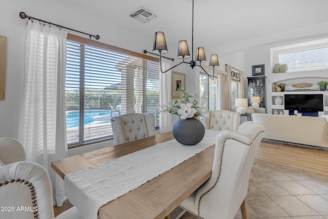 tiled dining area with a chandelier and a wealth of natural light