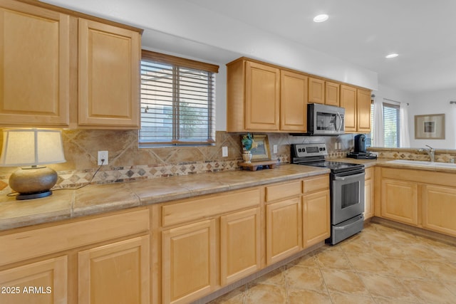 kitchen with tasteful backsplash, appliances with stainless steel finishes, light brown cabinetry, and sink